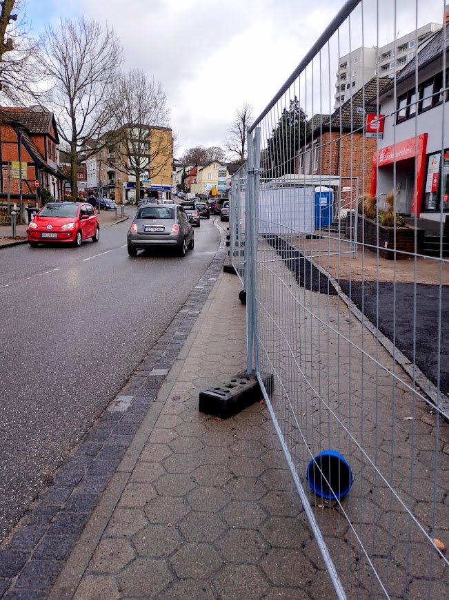 Blick entlang der Bahnhofstraße Reinbek: Die Baustellenabsperrung erzwingt einen Umweg, obwohl der mit eingezäunte Parkstreifen ausreichend Platz für einen barrierefreien Fußgängerweg geboten hätte.